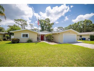 Charming single-story home with a well-maintained lawn, an American flag, and a welcoming red front door at 1891 Harmony Dr, Clearwater, FL 33756