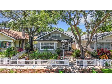 Charming home featuring mature trees, white picket fence, and a welcoming landscaped front yard at 231 15Th Ne Ave, St Petersburg, FL 33704
