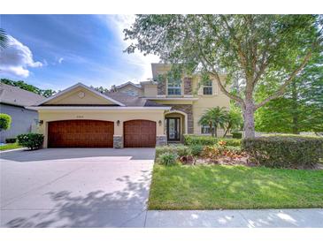 Charming two-story home featuring a three-car garage, manicured lawn, and mature landscaping at 3323 Anna George Dr, Valrico, FL 33596