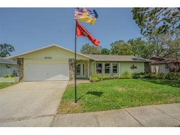 Charming single-story home featuring a well-manicured lawn, stone accents, and attached garage at 9930 121 N St, Seminole, FL 33772