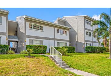 Low angle view of the property's exterior featuring lush landscaping and manicured lawn at 1351 Gulf Blvd # 209, Clearwater Beach, FL 33767