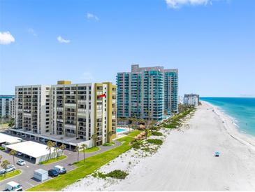 Aerial view of beachfront condos with pools, manicured lawns, and ample parking at 1480 Gulf Blvd # 1004, Clearwater Beach, FL 33767