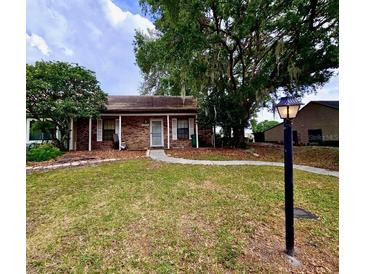 Charming brick home with a well-maintained lawn and mature trees, offering a cozy curb appeal at 35058 Whispering Oaks Blvd, Dade City, FL 33523