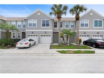 Gray townhome with a driveway, white garage door, and palm trees at 568 Shoreham Ne Ct, St Petersburg, FL 33716