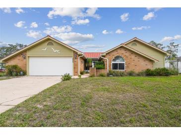 Charming single-story home featuring brick accents, light yellow siding, and a well-manicured front yard at 12371 Talpa St, Spring Hill, FL 34608
