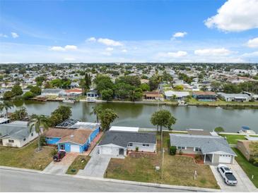 Waterfront homes featuring boat docks line a wide canal, offering scenic views under a partly cloudy sky at 2252 Society Dr, Holiday, FL 34691