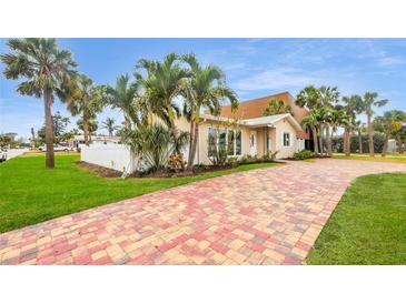 Beautiful single Gathering home with mature palms, green grass, and brick paver driveway at 281 44Th Ave, St Pete Beach, FL 33706