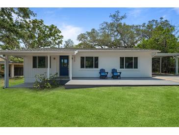 Charming single-story home featuring a well-maintained lawn, blue door, and an inviting front porch with two chairs at 608 Betmor Ln, Palm Harbor, FL 34683