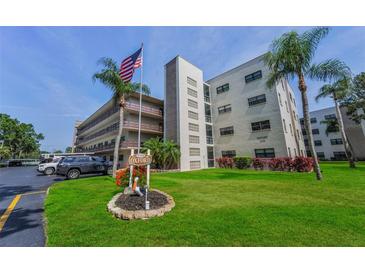 Well-maintained exterior of building, featuring an American flag, sign, palm trees, and attractive landscaping at 6190 80Th N St # 411, St Petersburg, FL 33709
