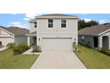 Charming two-story home featuring a two-car garage and well-maintained lawn at 13734 Whiskey Daisy Dr, Dade City, FL 33525