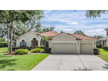 Stunning single-story home featuring a terracotta roof, lush landscaping, and an attached three-car garage at 18002 Avalon Ln, Tampa, FL 33647