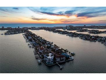 Expansive aerial view captures a waterfront community at sunset, showcasing stunning oceanfront property with pools and private docks at 5409 Pali Way, St Pete Beach, FL 33706