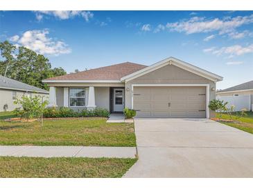 Charming single-story home featuring a two-car garage, landscaped yard, and neutral color palette at 6937 Gideon Cir, Zephyrhills, FL 33541