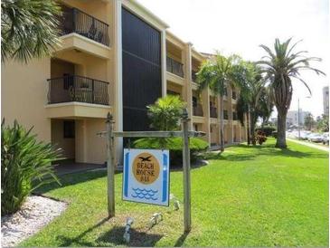 Condo exterior with lush lawn, palm trees and sign stating 