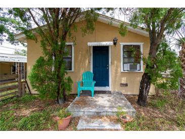 Charming home featuring a vibrant blue front door, complemented by a matching blue chair, creating a welcoming entrance at 1142 7Th Nw St, Largo, FL 33770