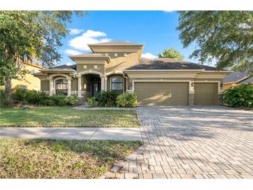Beautifully landscaped home with brick driveway, manicured lawn, and inviting curb appeal at 15104 Azra Dr, Odessa, FL 33556