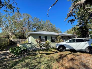 Charming single-story home with well-maintained lawn, complemented by mature trees and a modern white vehicle at 2221 York S St, Gulfport, FL 33707