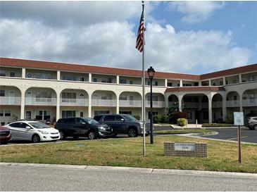 A sunny exterior view of the building with a flag in the front and multiple cars parked outside at 2434 Australia E Way # 50, Clearwater, FL 33763