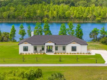 Stunning lakeside home featuring modern farmhouse architecture and lush green lawn at 3070 Smilodon Trl, Ruskin, FL 33570