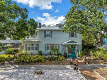 Charming two-story home with light green siding, lush landscaping, and a cozy second story balcony at 7427 4Th N Ave, St Petersburg, FL 33710