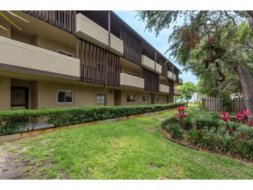 Multi-story building with brown trim and balconies surrounded by lush green landscaping at 1241 S Martin Luther King Jr Ave # 302, Clearwater, FL 33756