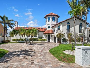 Stunning Mediterranean-style home showcasing a tower, red tile roof, circular driveway and lush landscaping at 191 1St W St, Tierra Verde, FL 33715
