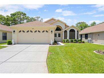 Charming single-story home featuring a two-car garage, well-manicured lawn, and inviting front entrance at 521 Bent Oak Ct, Spring Hill, FL 34609
