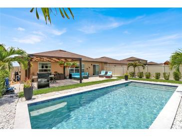 Sparkling pool with poolside lounge area and covered outdoor kitchen perfect for entertaining at 7114 Fern Garden Ct, Sun City Center, FL 33573