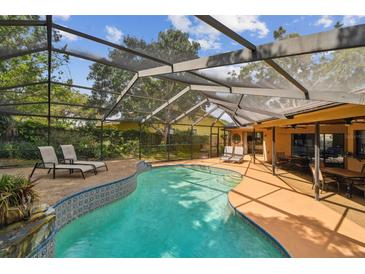 A screened pool is surrounded by lounge seating and a dining area, perfect for outdoor entertaining at 854 Village Way, Palm Harbor, FL 34683