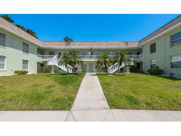 Charming condo building with lush landscaping, white railings, and a welcoming entrance at 1250 S Pinellas Ave # 214, Tarpon Springs, FL 34689