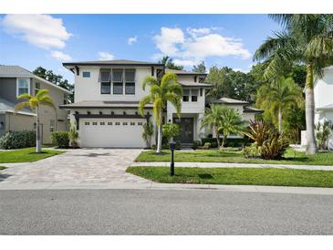 Beautiful two-story home featuring a well-manicured lawn, brick driveway, and palm trees at 12705 Green Heron Way, Odessa, FL 33556