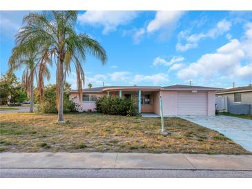 Charming single-story home with a well-kept lawn and a palm tree in the front yard at 3243 Eisenhower Dr, Holiday, FL 34691