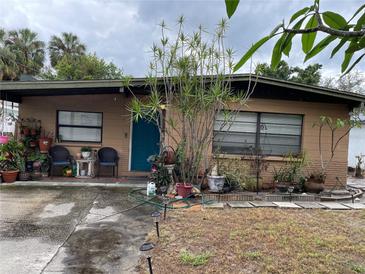 Charming single-story home featuring a quaint front porch, teal door, and a well-maintained lawn at 4104 W North B St, Tampa, FL 33609
