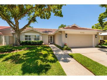 Charming home featuring a well-maintained lawn, a red tile roof, and a two-car garage at 5242 Venice Ne Way, St Petersburg, FL 33703