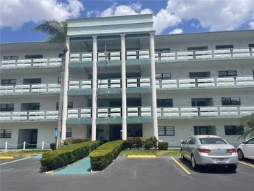 A three-story condo building with white pillars, blue trim, and parking spaces in front at 5970 80Th N St # 204, St Petersburg, FL 33709