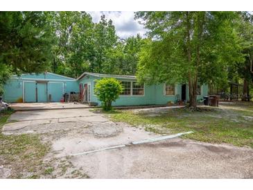 Single story home featuring a large yard with mature trees, showcasing its potential for outdoor enjoyment at 10854 Telford St, New Port Richey, FL 34654