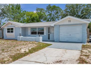Charming single-story home with a well-maintained lawn and attached garage, painted in a cool, light blue at 10900 Queens Rd, Port Richey, FL 34668