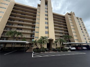 An exterior view of a multi-story residential building featuring parking and palm tree landscaping at 2621 Cove Cay Dr # 206, Clearwater, FL 33760