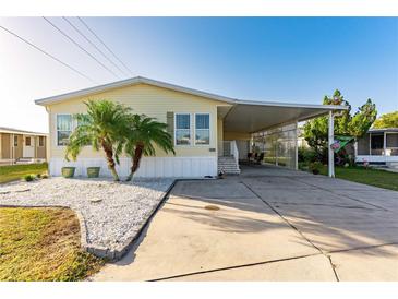 Charming yellow home features a covered carport, palm trees, and a well-maintained yard, offering a warm and inviting curb appeal at 37338 Sandra Ave, Zephyrhills, FL 33542
