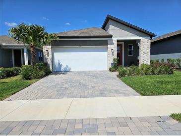 Charming single-Gathering home with a lush green yard, a paved driveway, and a two-car garage at 3776 Maxwell Park Dr, Sun City Center, FL 33573