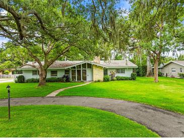 Charming single-story home with stone accents, mature trees, and a well-manicured lawn at 1675 Robin Hood Ln, Clearwater, FL 33764