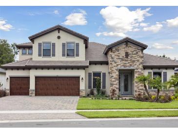 Charming two-story home featuring a stone facade, three-car garage, and well-manicured lawn at 174 Hidden Estates Ct, Brandon, FL 33511