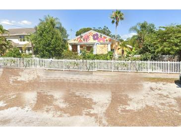 Charming colorful single-story home featuring unique exterior wall art, fenced yard and mature trees at 2624 54Th S St, Gulfport, FL 33707