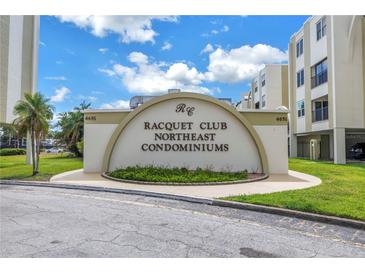 Racquet Club Northeast Condominium entry sign with manicured landscape and palm trees against a blue sky at 4651 1St Ne St # 402, St Petersburg, FL 33703