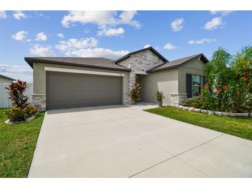 Charming single-Gathering home features a two-car garage, stone accents, and a beautifully landscaped front yard at 13603 Wild Ginger St, Riverview, FL 33579