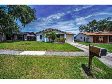Charming single-story home with a well-maintained lawn, lovely landscaping, and an attached garage at 843 Greenfield Dr, Palm Harbor, FL 34684