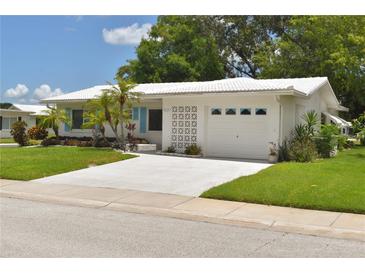 Charming single-story home with a white tile roof, bright shutters, an attached garage, and well-manicured landscaping at 9639 Mainlands E Blvd, Pinellas Park, FL 33782