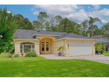 Charming home with manicured lawn, arched entry, paver driveway, and attached two-car garage at 13038 Royal George Ave, Odessa, FL 33556
