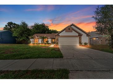 Charming single-Gathering home boasts stone accents, manicured lawn, two-car garage, and lovely twilight sky at 1308 Peachfield Dr, Valrico, FL 33596