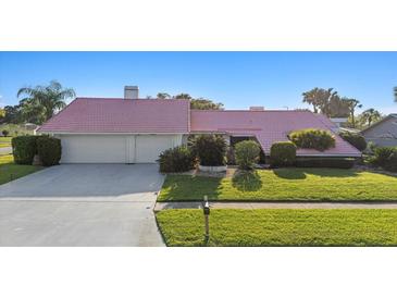 Charming single-story home featuring a unique pink roof and well-maintained landscaping at 2886 Green Meadow Ct, Clearwater, FL 33761